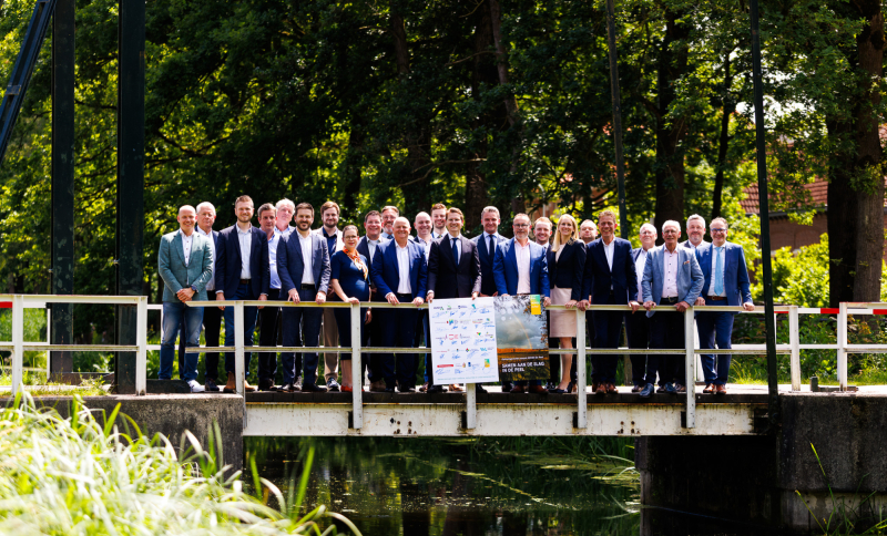 Groepsfoto van bestuurders en partners op een brug in De Peel, bij aankondiging van investering in natuur, water en stikstofreductie.