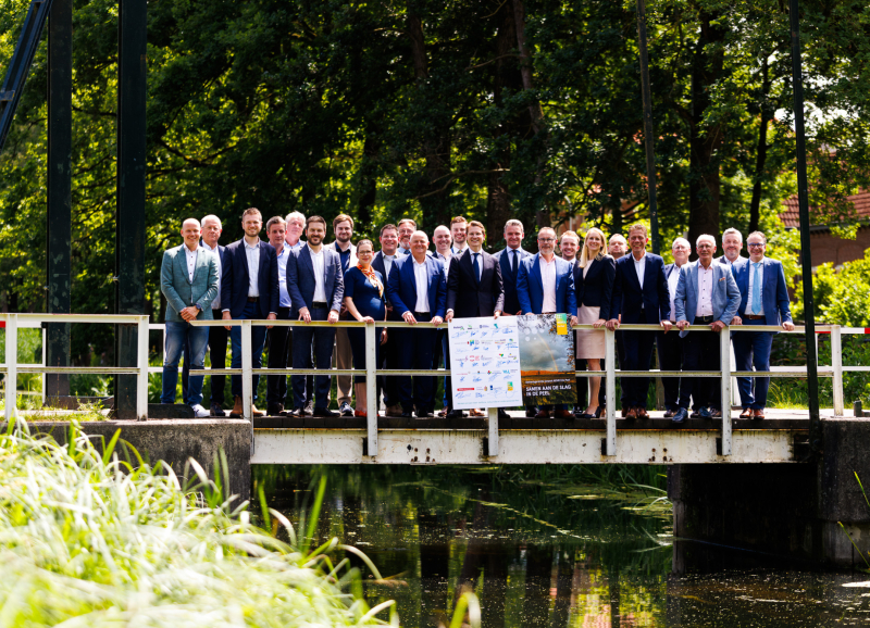Groepsfoto van bestuurders en partners op een brug in De Peel, bij aankondiging van investering in natuur, water en stikstofreductie.