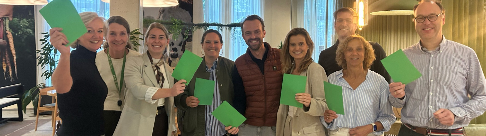 Groepsfoto van de partners van Jump naast elkaar op een rij met elk een groene kaart in de hand