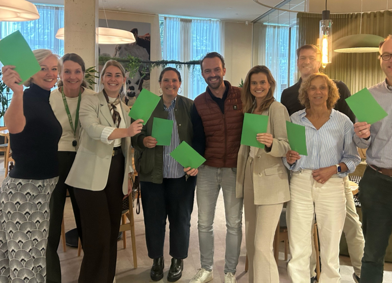 Groepsfoto van de partners van Jump naast elkaar op een rij met elk een groene kaart in de hand