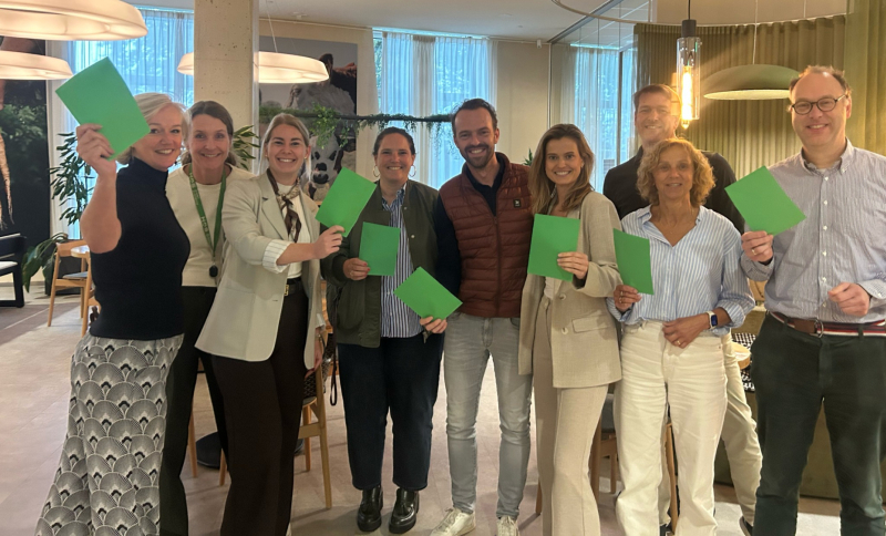 Groepsfoto van de partners van Jump naast elkaar op een rij met elk een groene kaart in de hand