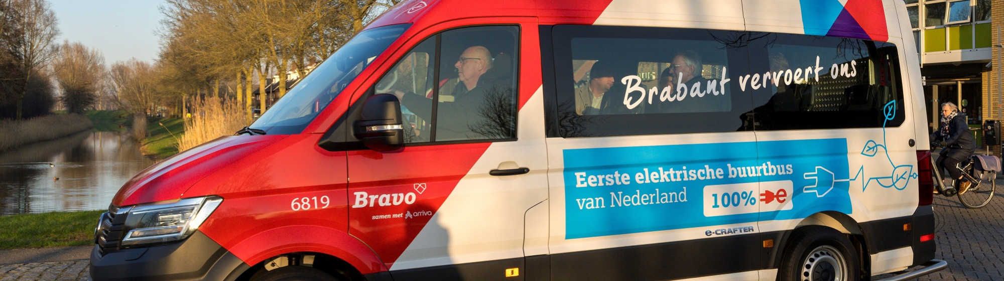 De eerste elektrische buurtbus van de zijkant met voorin de bestuurder.