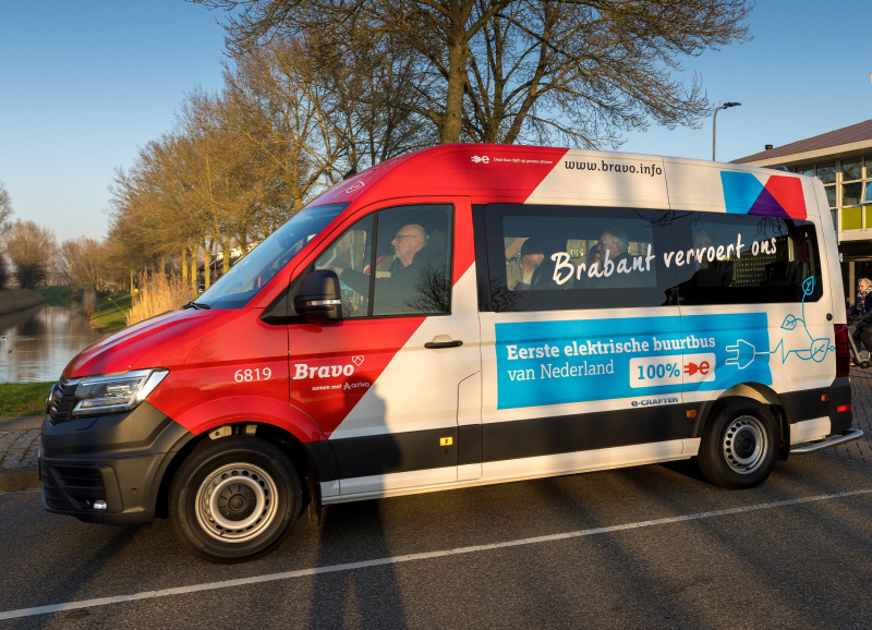De eerste elektrische buurtbus van de zijkant met voorin de bestuurder.