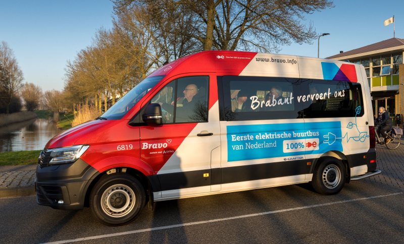 De eerste elektrische buurtbus van de zijkant met voorin de bestuurder.