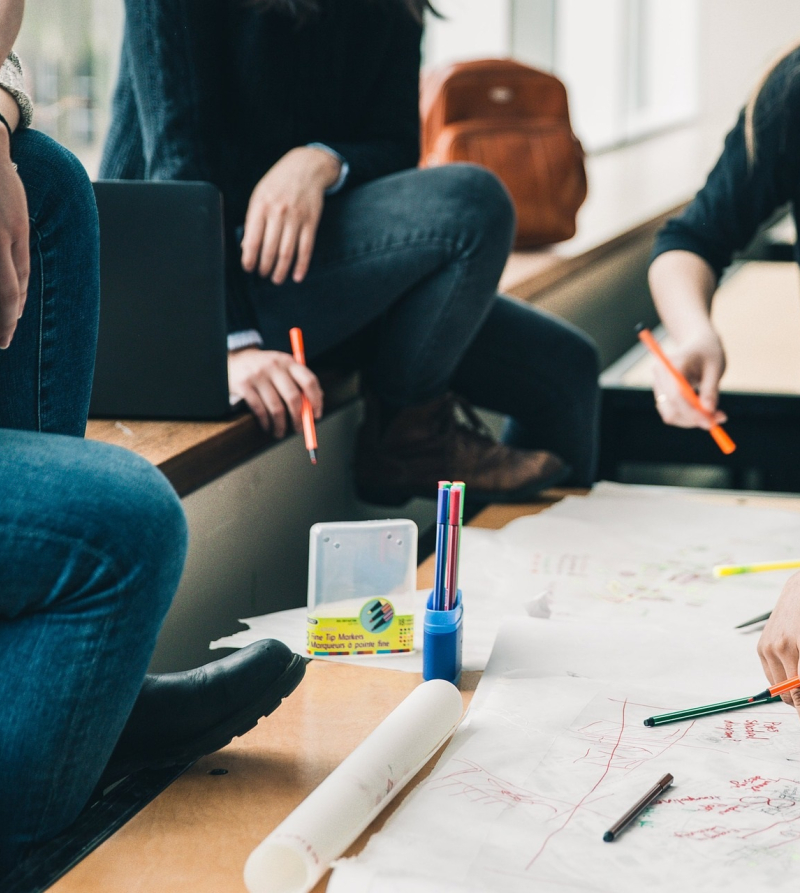 Foto met jongeren aan een tafel die samen op een vel papier schrijven