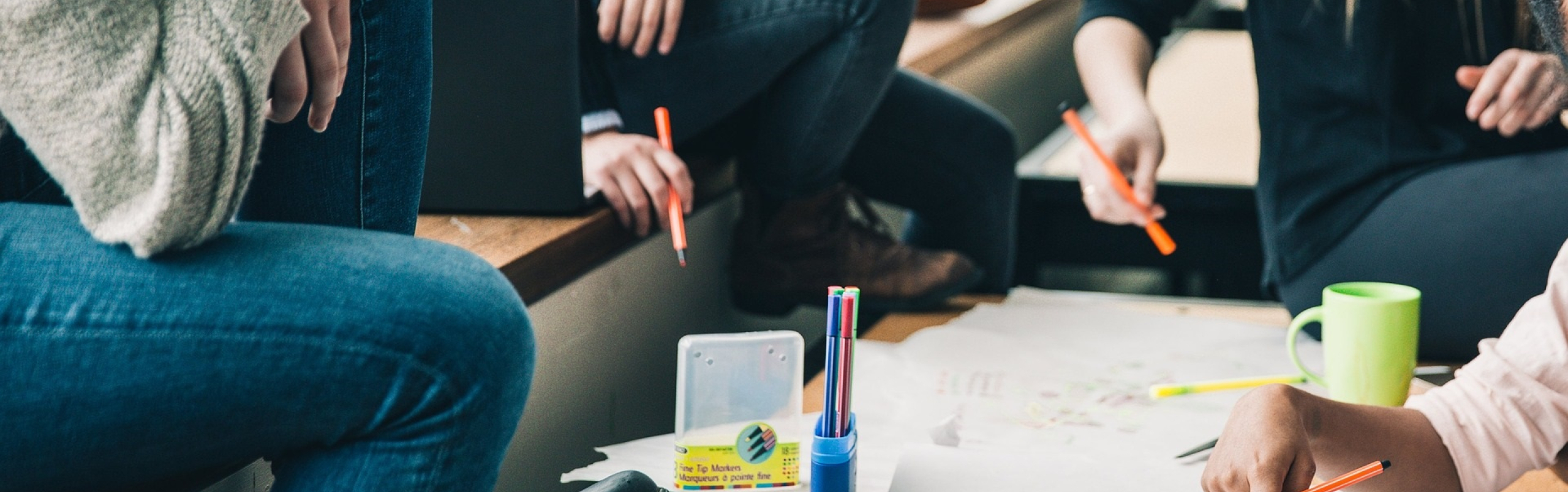 Foto met jongeren aan een tafel die samen op een vel papier schrijven