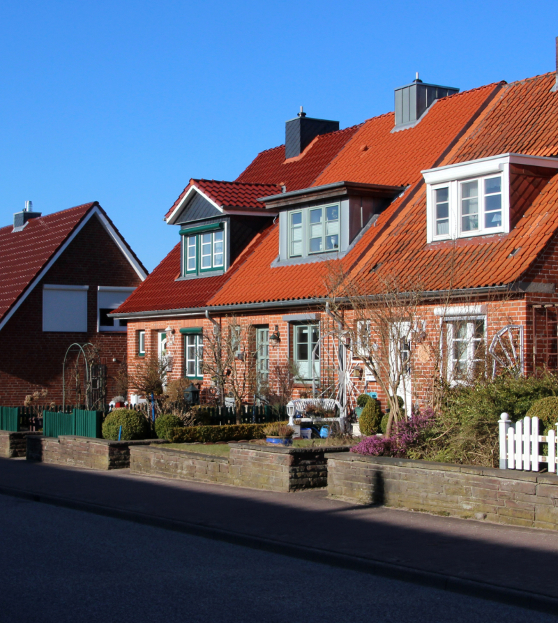 Foto van een rijtje huizen uit de jaren 50-60 met zicht op de voortuinen
