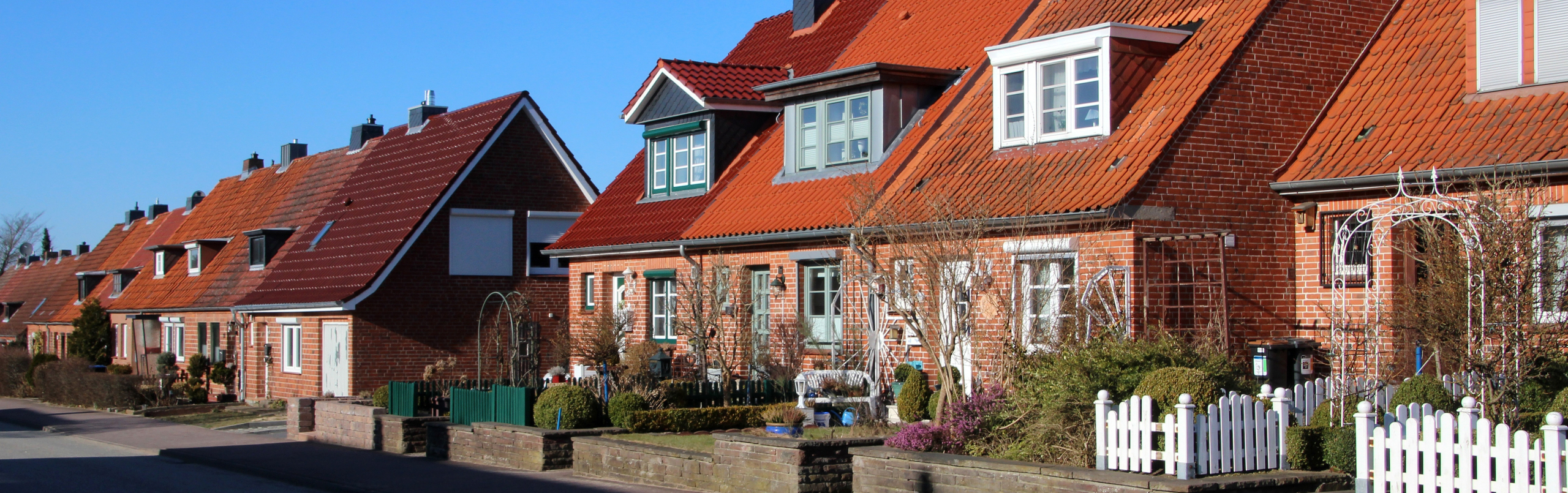 Foto van een rijtje huizen uit de jaren 50-60 met zicht op de voortuinen
