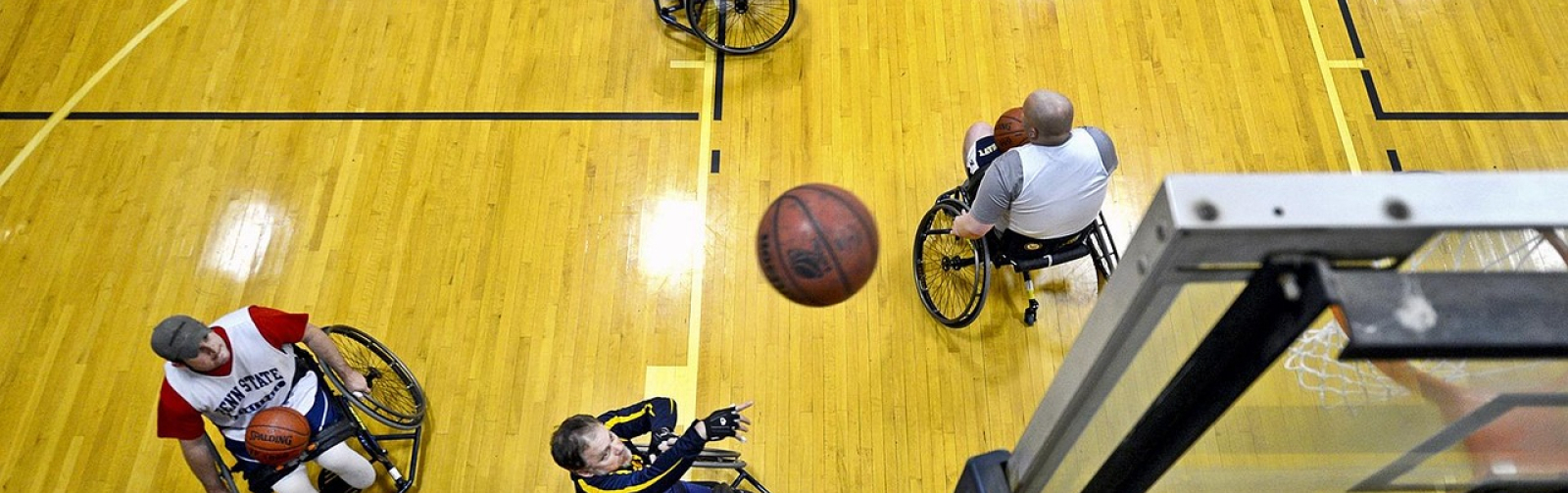 Foto van sporters in een rolstoel die basketbal spelen