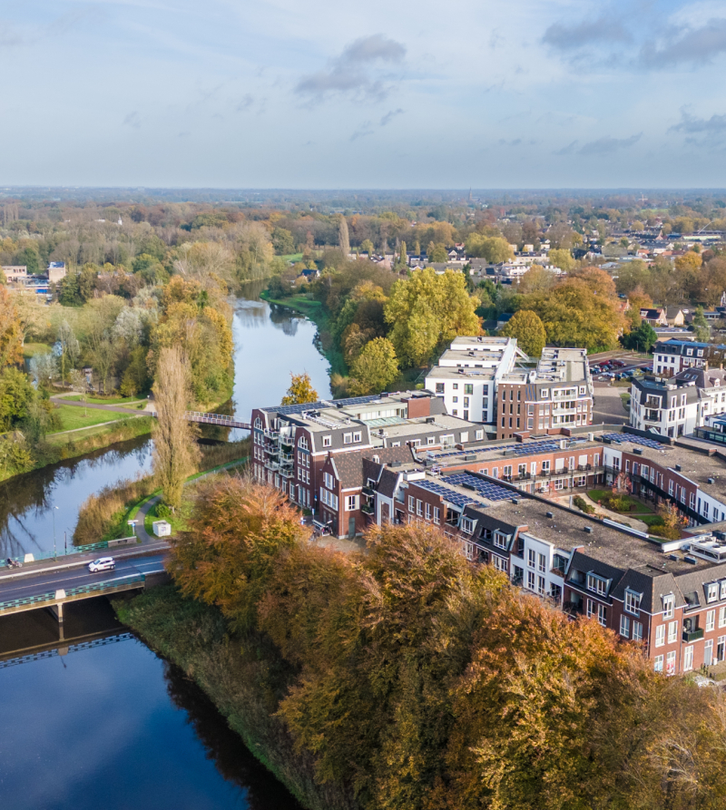 Foto met bovenaanzicht van Sint-Michielsgestel aan een kanaal, met veel water en groen