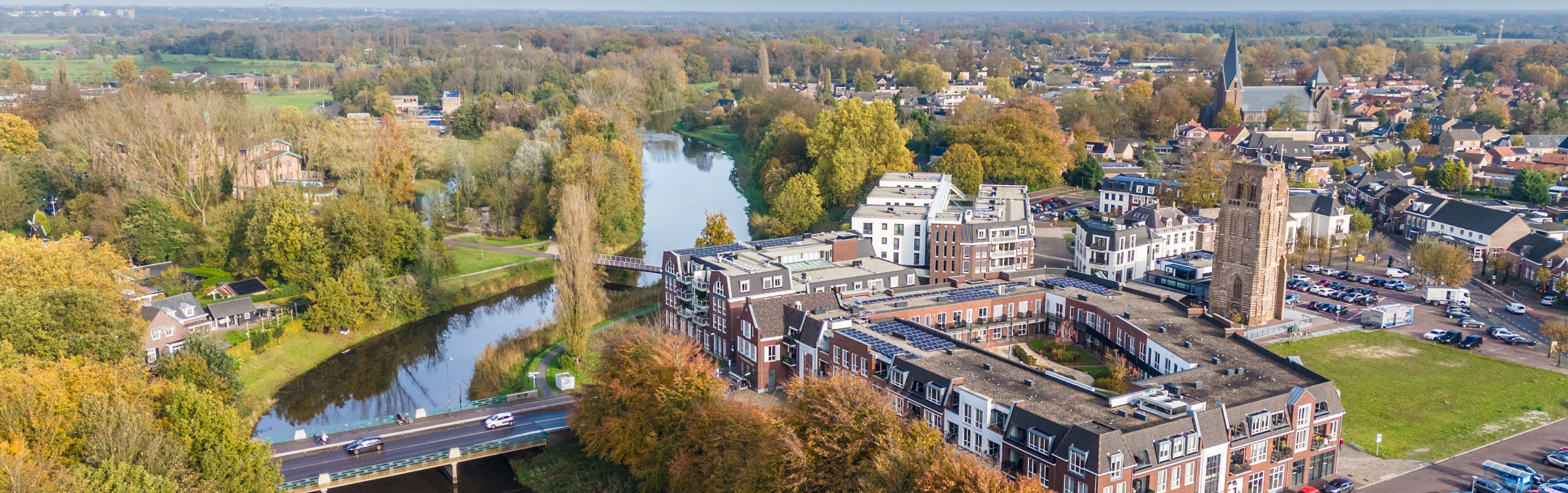 Foto met bovenaanzicht van Sint-Michielsgestel aan een kanaal, met veel water en groen