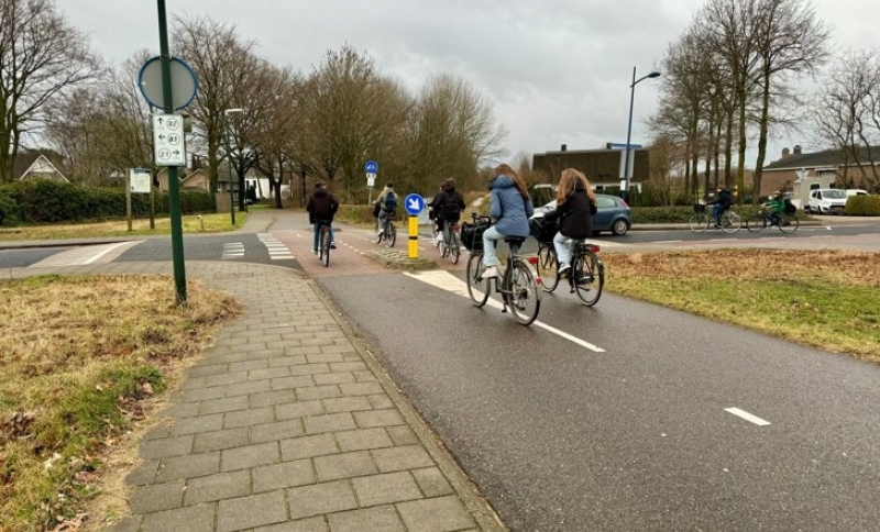 Jongeren steken kruising over, fietsend op een fietspad