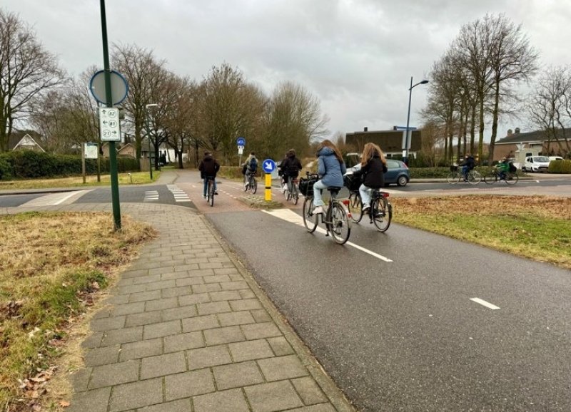 Jongeren steken kruising over, fietsend op een fietspad
