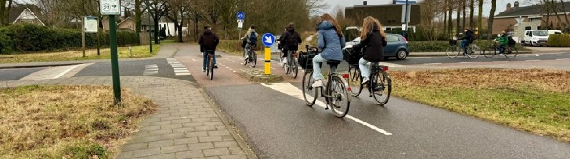 Jongeren steken kruising over, fietsend op een fietspad