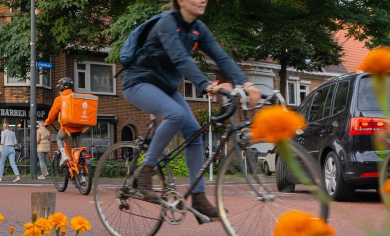 Fietsende dame en thuisbezorger van maaltijden op de fiets