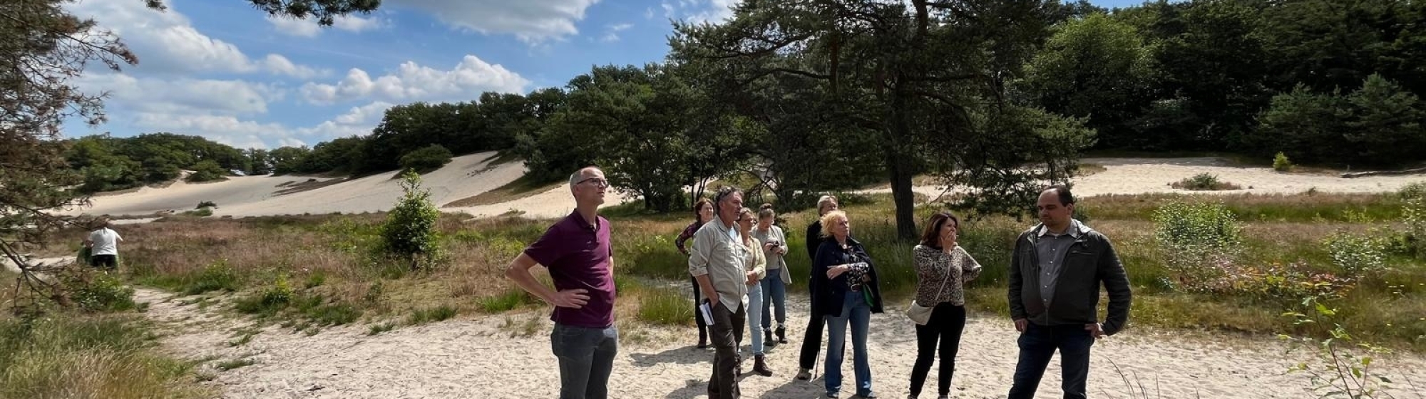 Groepje van 9 ambtenaren lopen op een zandpad in de Loonse en Drunense duinen