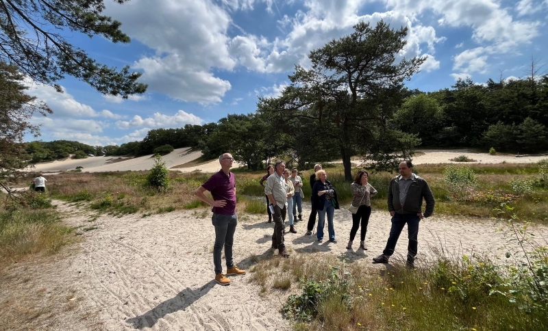 Groepje van 9 ambtenaren lopen op een zandpad in de Loonse en Drunense duinen