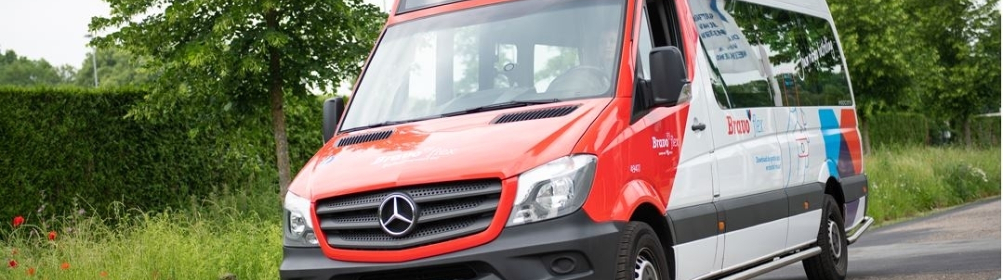 OV busje op een B-weg in landelijk gebied 