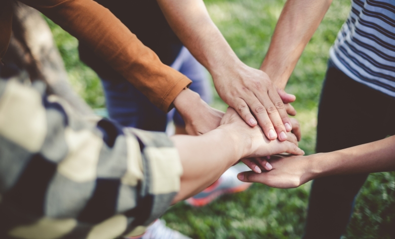 Vier mensen die de handen op elkaar doen