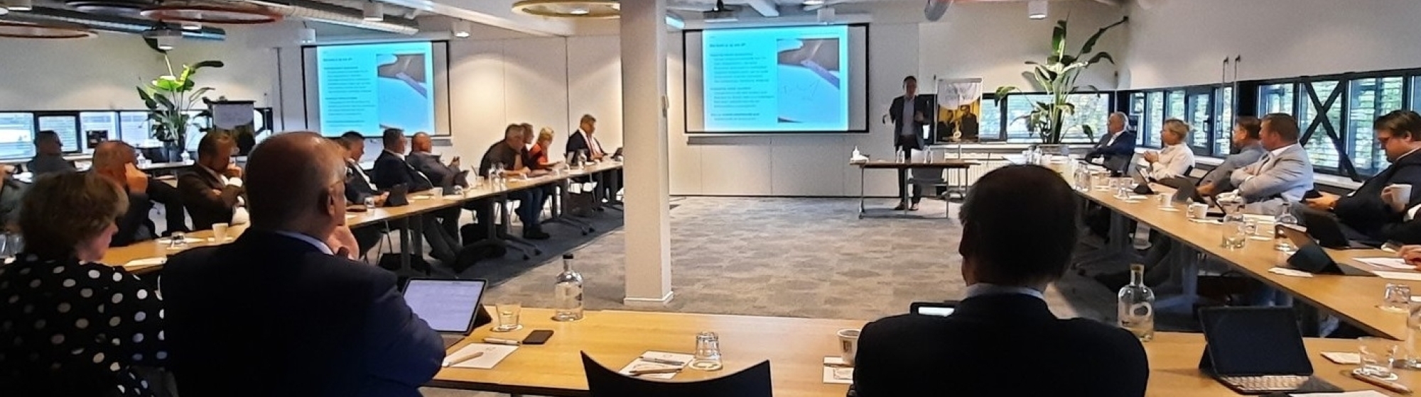 Bestuurders uit de regio zitten aan tafel in een U-vorm