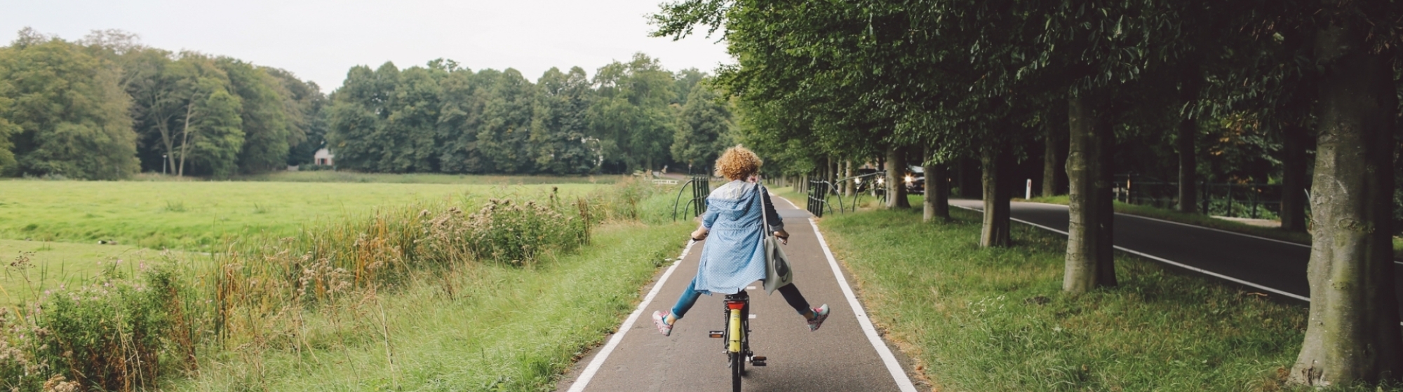 Meisje fietst langs een weiland op een fietspad 