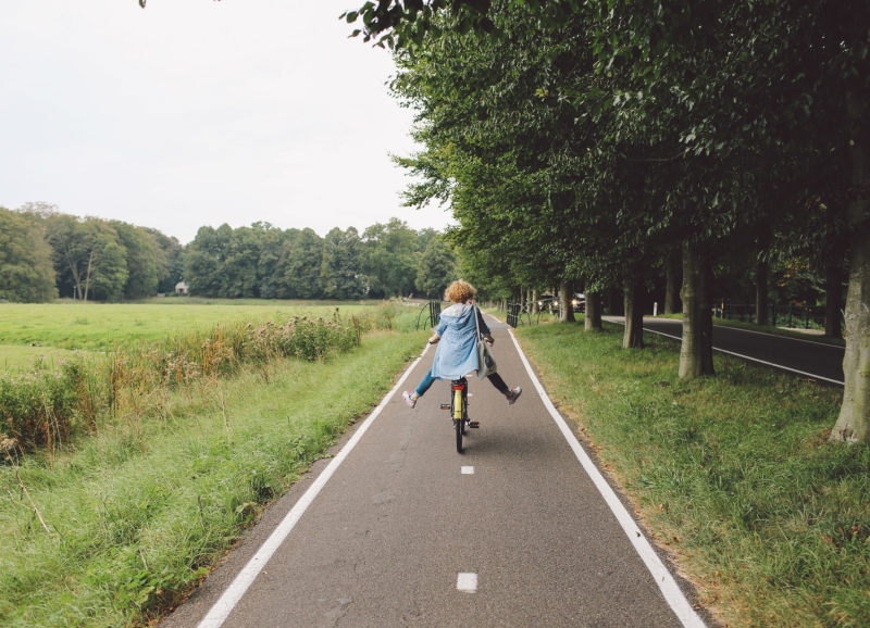 Meisje fietst langs een weiland op een fietspad 