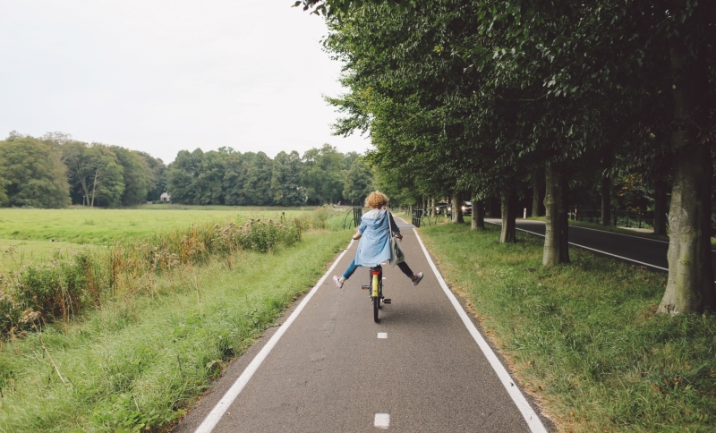 Meisje fietst langs een weiland op een fietspad 