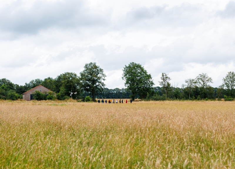 Een groepje mensen wandelt achter elkaar door een natuurgebied in de Peel