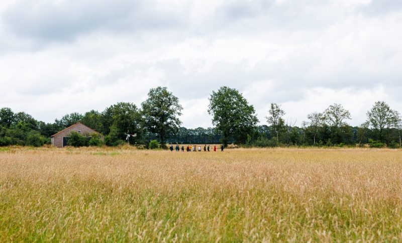 Een groepje mensen wandelt achter elkaar door een natuurgebied in de Peel
