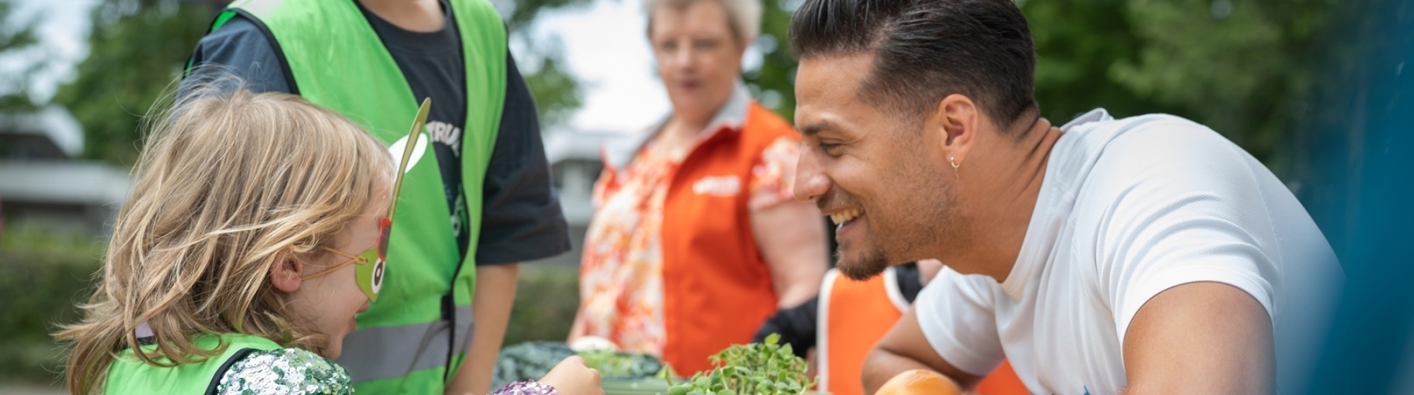Juvat Westendorp, ambassadeur van Jon Leren eten, proeft samen met een meisje op de BSO groenten.