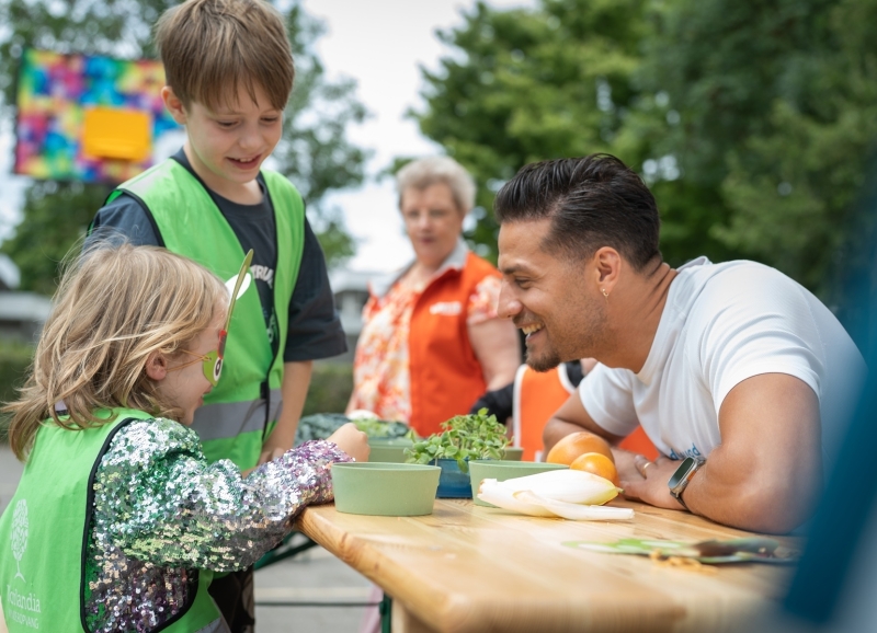 Juvat Westendorp, ambassadeur van Jon Leren eten, proeft samen met een meisje op de BSO groenten.