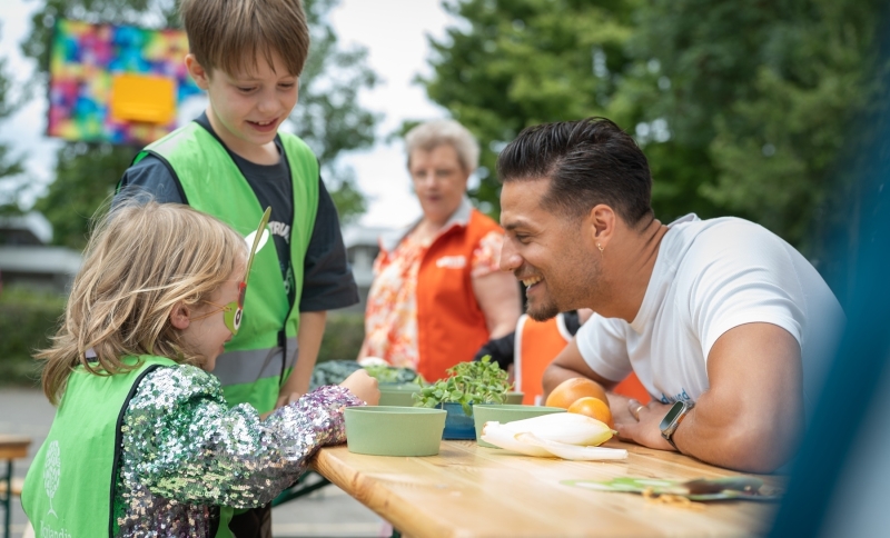 Juvat Westendorp, ambassadeur van Jon Leren eten, proeft samen met een meisje op de BSO groenten.