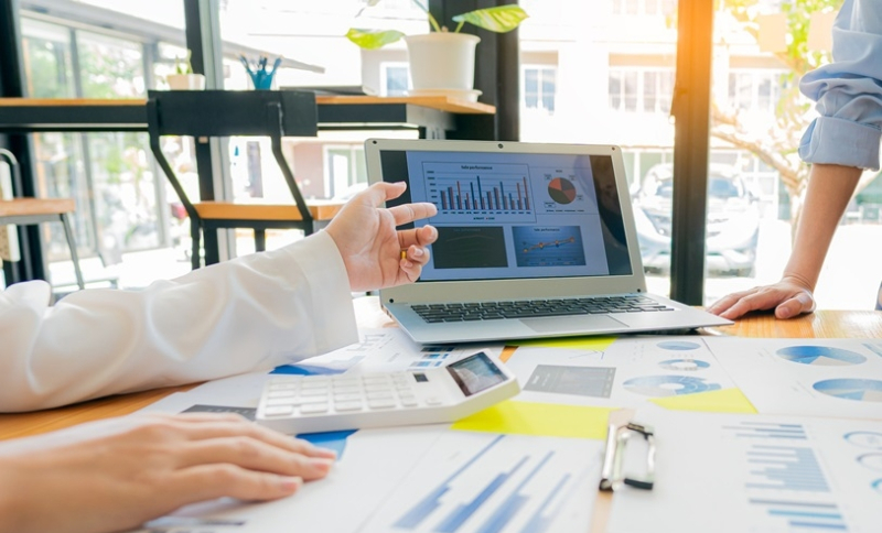 Closup van werktafel met documenten, laptop en handen van mensen