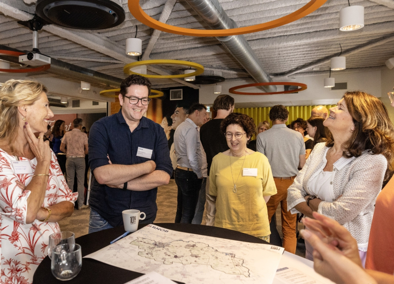 Ambtenaren uit de regio staan rond een tafel met landkaart en document