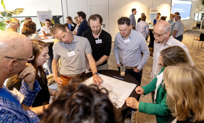 Ambtenaren uir de regio staan rond een statafel met documenten