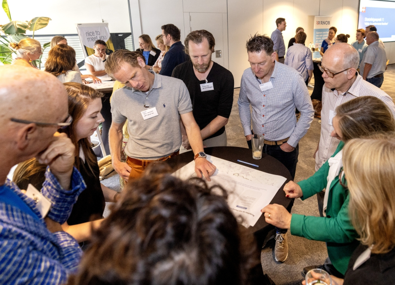 Ambtenaren uir de regio staan rond een statafel met documenten