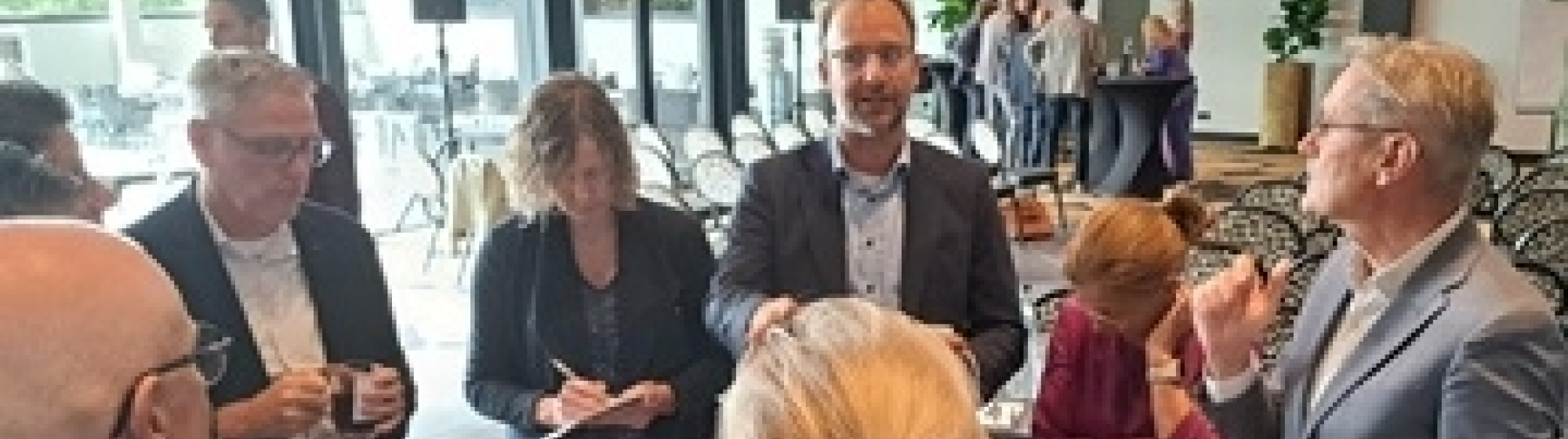 Bestuurders en ambtenaren met elkaar in gesprek rond een hoge tafel