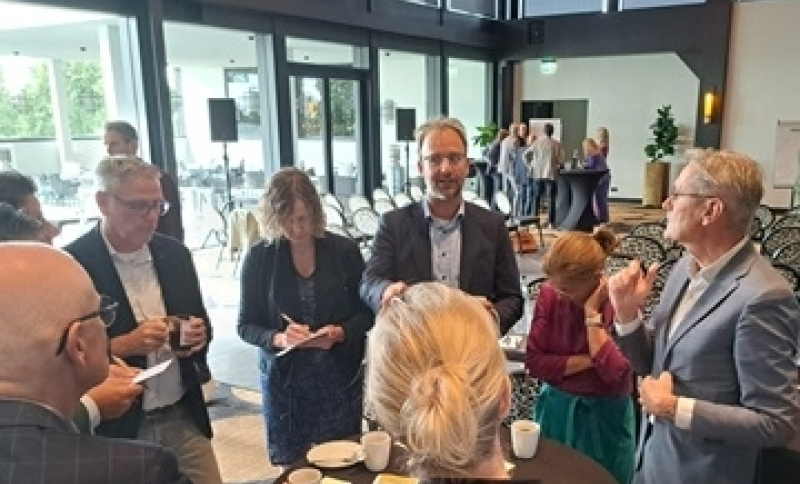 Bestuurders en ambtenaren met elkaar in gesprek rond een hoge tafel