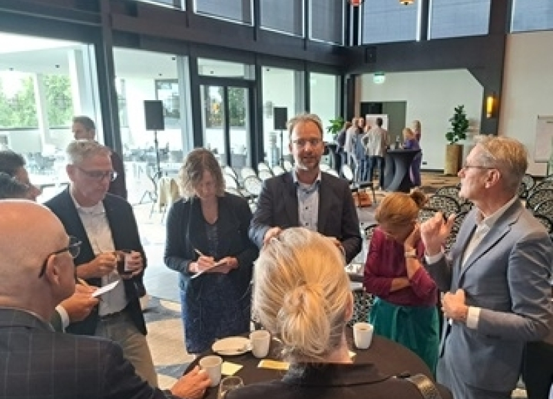 Bestuurders en ambtenaren met elkaar in gesprek rond een hoge tafel