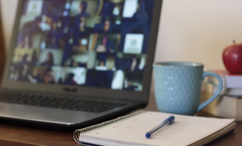 Laptop met schrift, pen, appel en mok ernaast