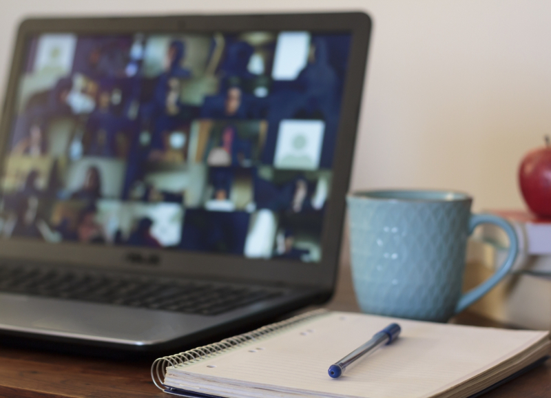 Laptop met schrift, pen, appel en mok ernaast