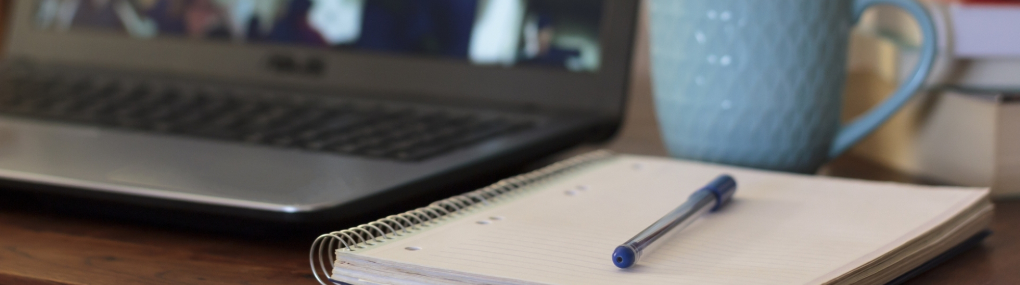 Laptop met schrift, pen, appel en mok ernaast