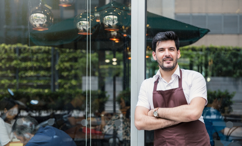 Restauranthouder leunt tegen raam van zijn bedrijf aan