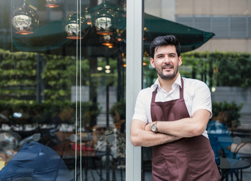 Restauranthouder leunt tegen raam van zijn bedrijf aan