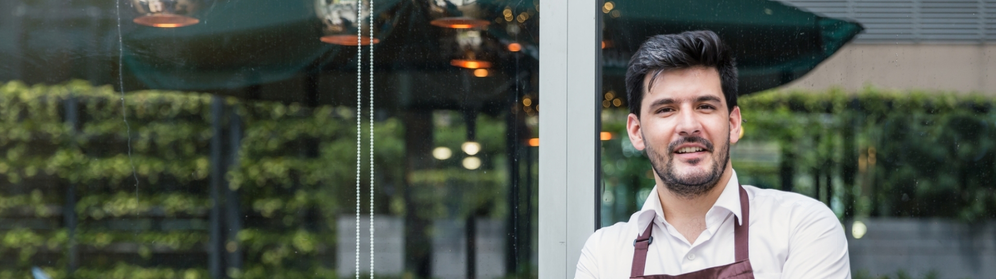 Restauranthouder leunt tegen raam van zijn bedrijf aan