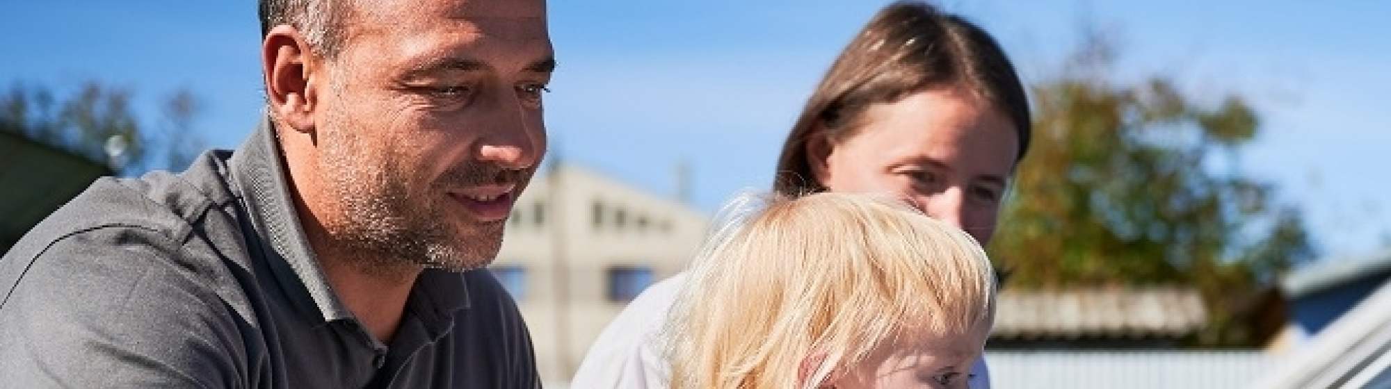 Vader, moeder en kind bij een kas