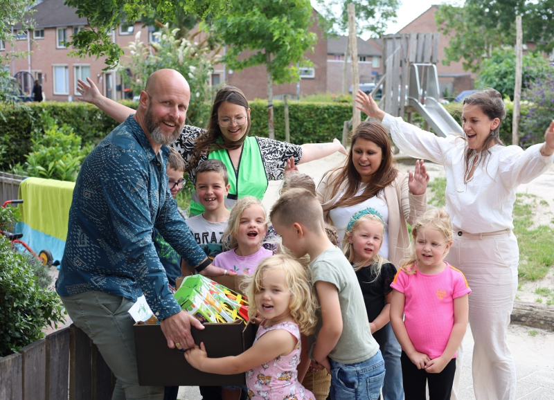 Wethouder, BSO leidsters en kinderen houden een groentenpakket vast