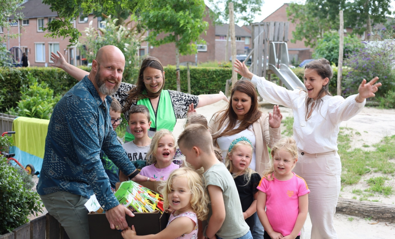 Wethouder, BSO leidsters en kinderen houden een groentenpakket vast