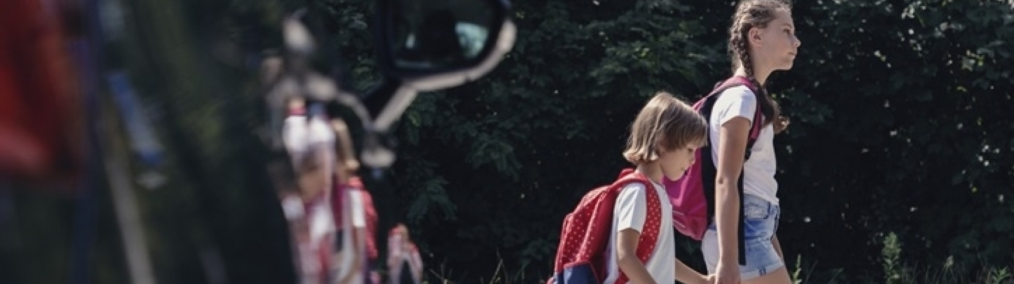 Kinderen steken over bij een zebrapad met een auto ervoor