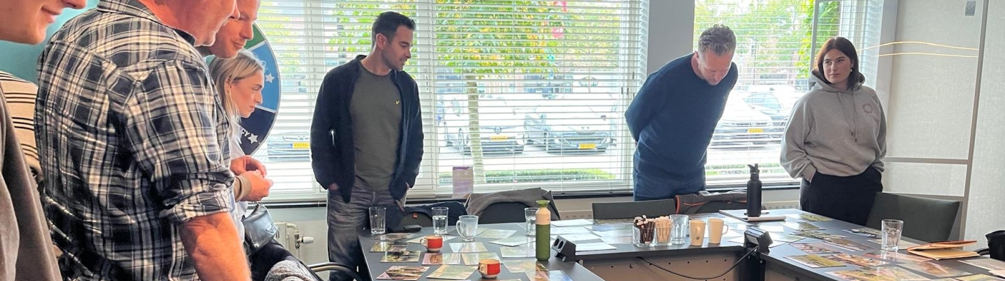 Gemeenteambtenaren met elkaar in gesprek aan een tafel in U vorm met kaarten erop